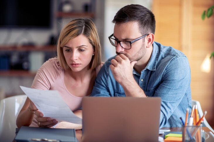 family managing budget, reviewing their bank accounts using laptop in kitchen