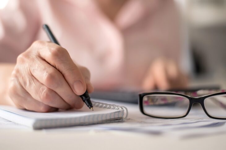 pension calculation concept, old hands counting finances on a home calculator , close- up