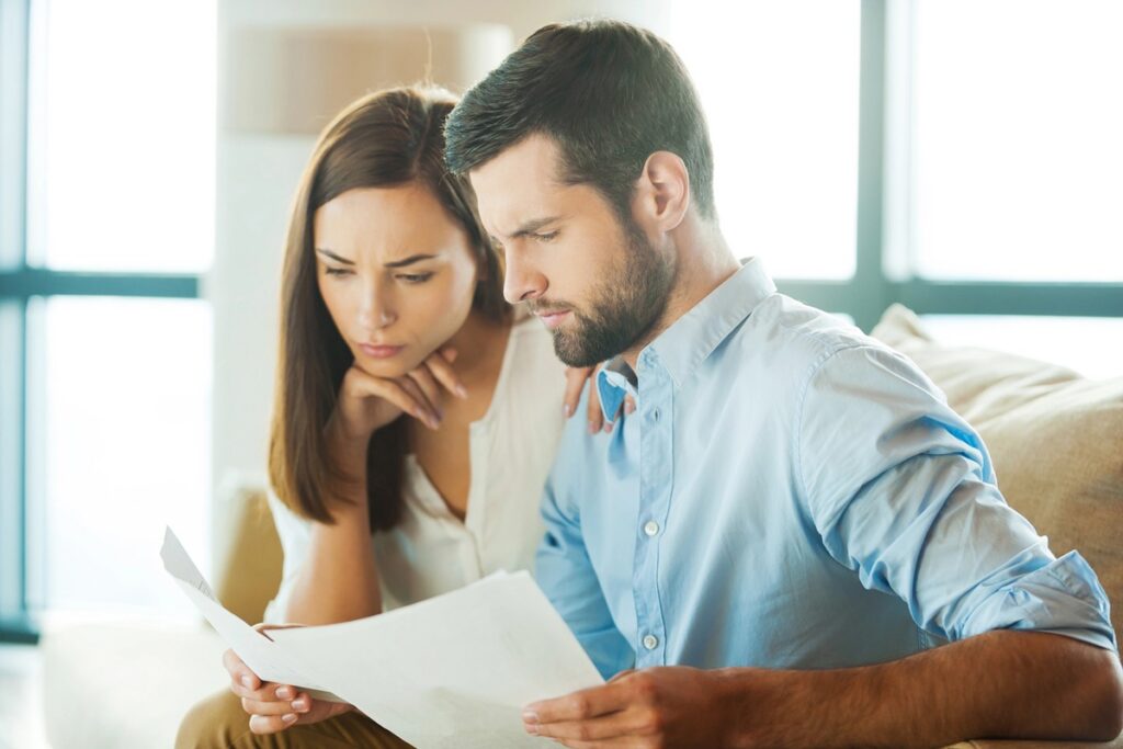 Young couple at table looking at document or finances